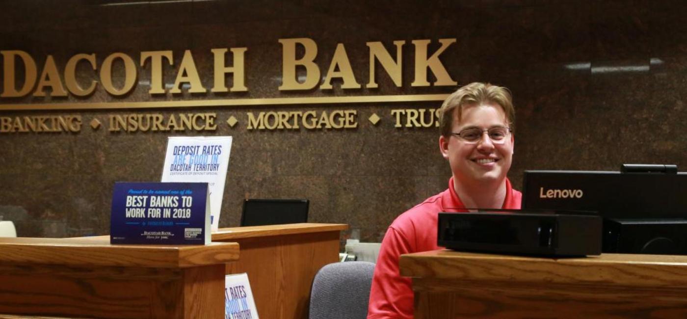 Bank teller smiling at desk in Dacotah Bank