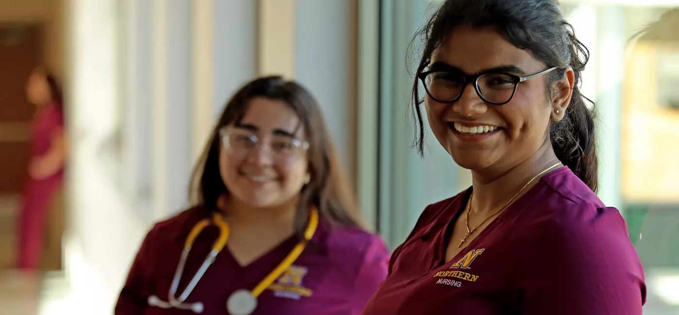 Two female nursing students standing in a hallway