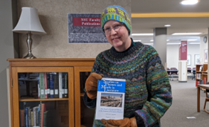 Ginny Lewis holds her new book in the NSU Library